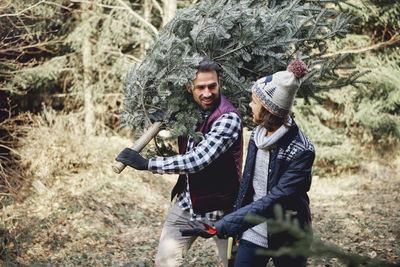 Mature man with branch walking along with teenage boy in forest