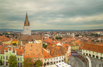 Aerial view of townscape against cloudy sky