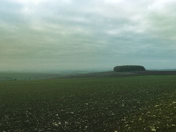 Scenic view of field against cloudy sky