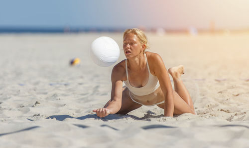 Young woman in bikini playing volleyball
