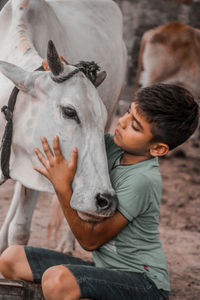 Cute boy embracing with cow outdoors