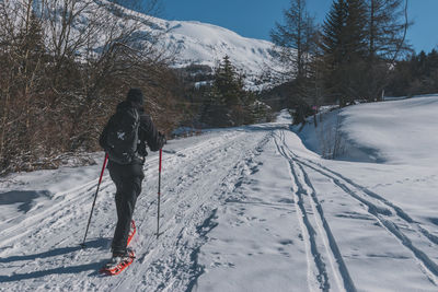 An unrecognizable male hiker wearing snowshoes walking in the french alps