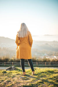 Rear view of woman standing on land against sky