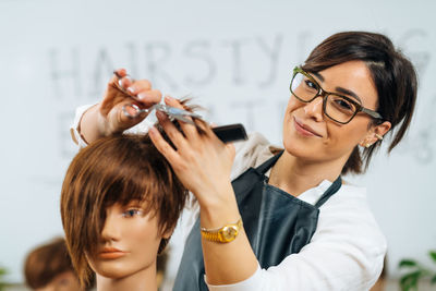 Portrait of female hairstyling educator during training in hair salon, smiling and looking at camera