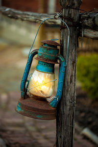 Close-up of old-fashioned lantern hanging from wooden railing