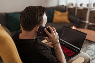 Young woman using phone while sitting at home