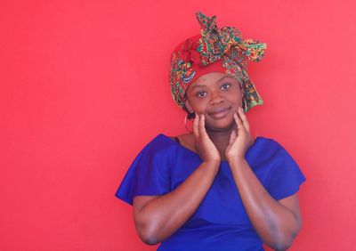 Portrait of a smiling young woman against red wall