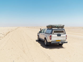 Vintage car on desert land against clear sky