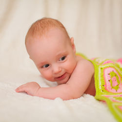 Portrait of cute baby girl lying on bed