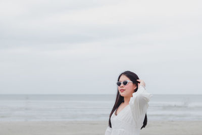 Young woman wearing sunglasses standing on beach