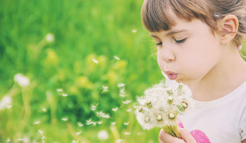Close-up of young woman blowing flowers
