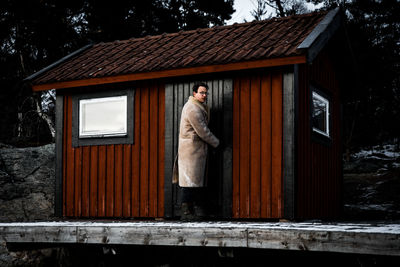 Portrait of mid adult man standing by house during winter