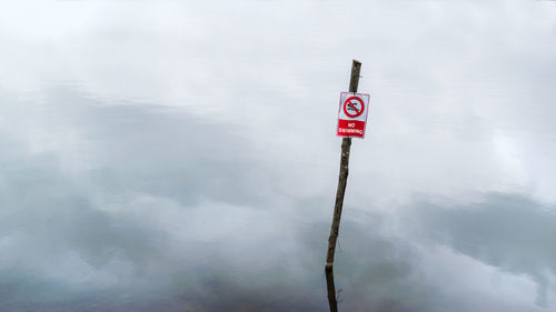 Information sign on wooden post in lake