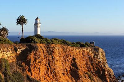 Lighthouse by sea against sky