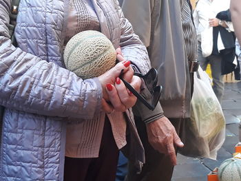 Midsection of woman with cantaloupe standing by man on street market