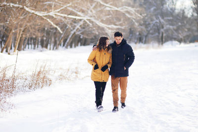 Rear view of friends walking on snow covered land