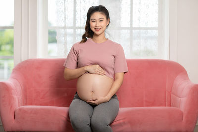 Portrait of a smiling young woman sitting on sofa