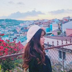 Woman standing by buildings in city against sky