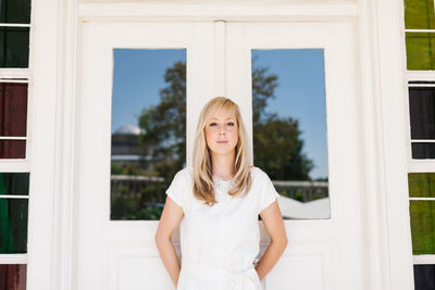 Portrait of beautiful woman standing against closed door