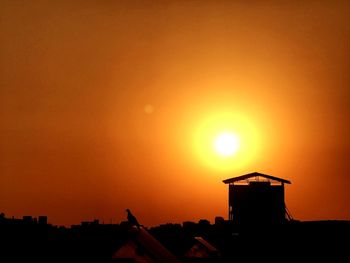 Silhouette buildings against orange sky