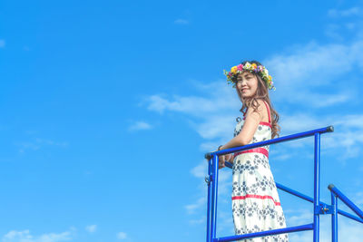 Low angle view of woman looking away against blue sky