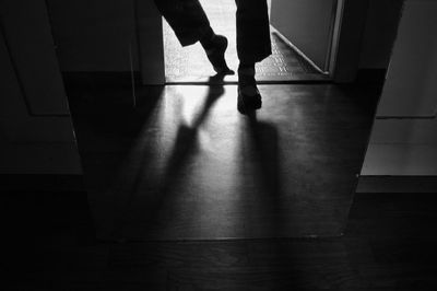 Low section of silhouette woman walking on floor