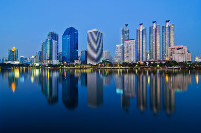 Reflection of buildings in lake against blue sky