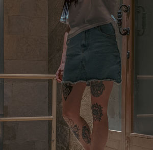 Low section of woman standing against wall