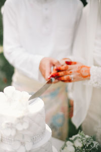 Close-up of couple cutting weeding cake