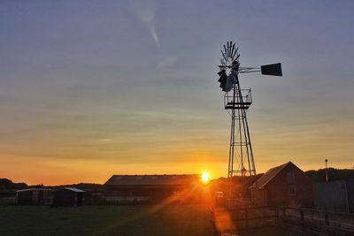 Crane by building against sky during sunset