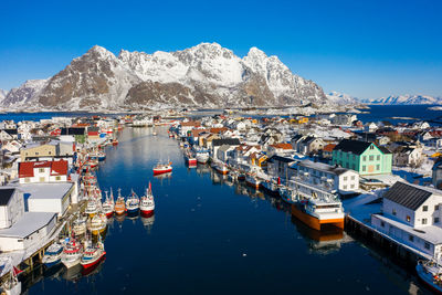 Sailboats moored in sea by buildings against sky