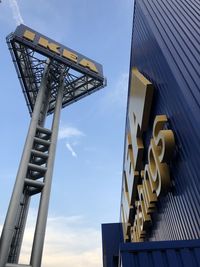 Low angle view of crane by building against sky