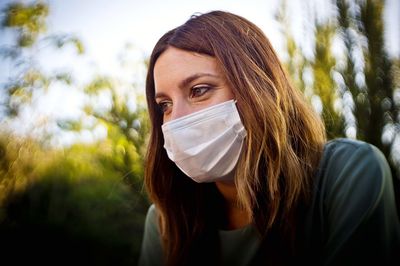 Close-up of woman wearing mask sitting outdoors