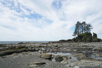 Rocks on shore by sea against sky