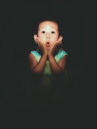 Portrait of cute boy against black background