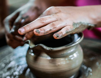 Close-up of hands making pot on pottery wheel