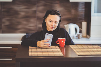 Young woman using smart phone at cafe table