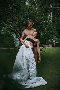 Young couple sitting on grass against trees