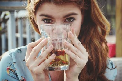 Close-up portrait of a young woman drinking glass