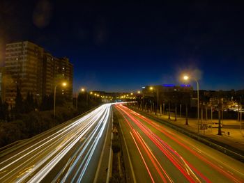 Light trails on road against sky at night