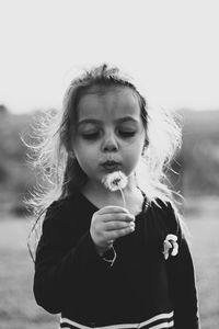 Close-up of cute girl blowing dandelion