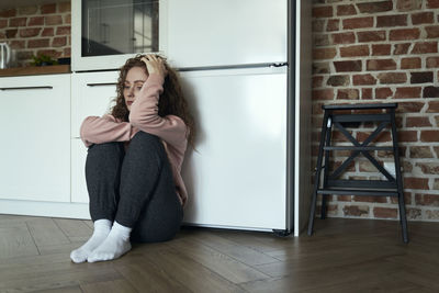 Portrait of young woman standing against wall