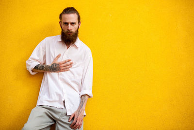 Portrait of young man standing against yellow background