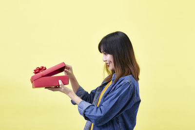 Side view of smiling young woman against gray background