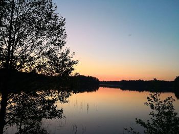 Silhouette tree by lake against sky during sunset