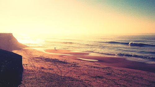 Scenic view of beach against clear sky during sunset