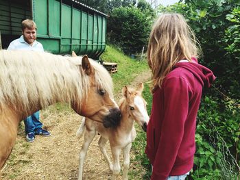 Father and daughter standing by horses on field