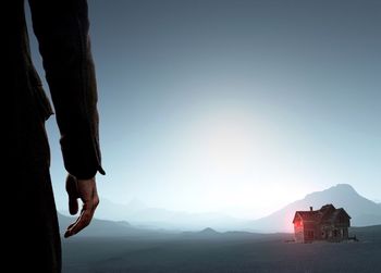 Low section of man on mountain against clear sky