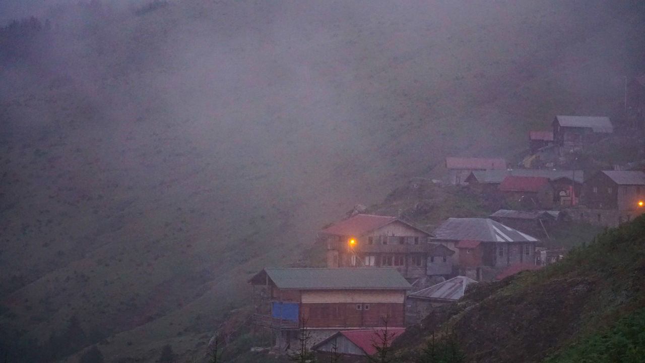 architecture, building exterior, built structure, fog, building, house, nature, no people, residential district, city, environment, night, outdoors, roof, illuminated, mountain, high angle view, landscape, smoke, sky