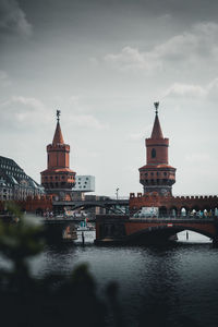 Bridge over river by buildings against sky in city